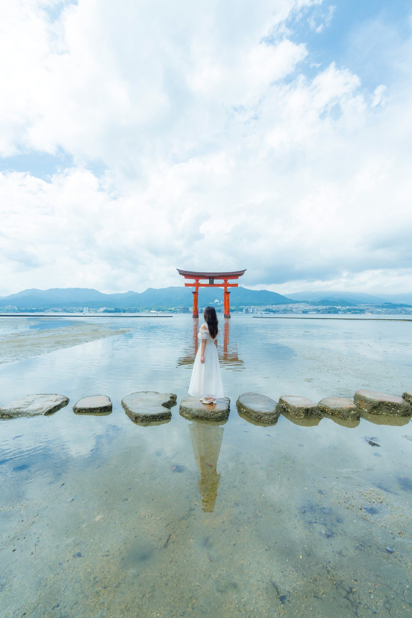 A figure in white on the tidal stepping stones before the great torii