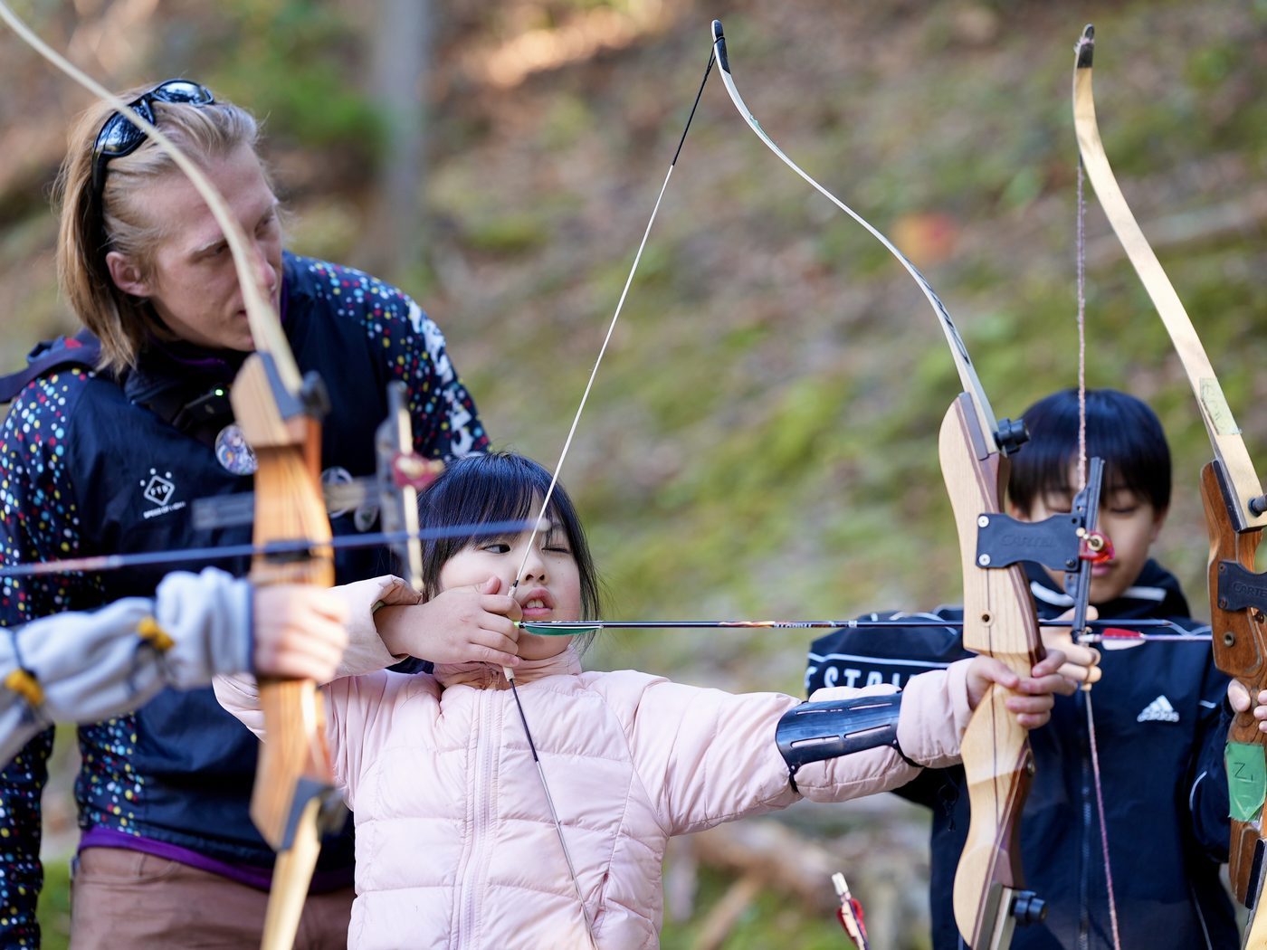 子どもに弓の引き方を教えるガイド